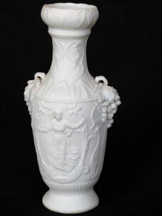 [Amphora-shaped parian vase with glazed interior, applied grape clusters at shoulders with high relief classically attired female figure with floral motif on body with background mottling]