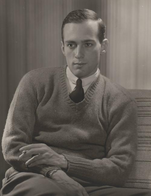 [Portrait of a male, seated, holding a cigarette]