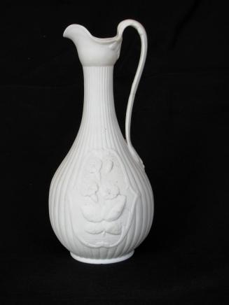 [Pear-shaped parian ewer with body fluting and high relief vine-framed floral motif with background mottling]