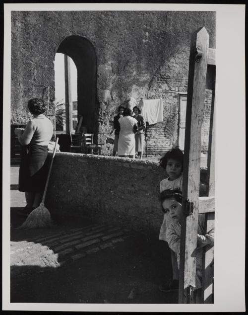 Children peeping out behind yard fence, Rome, Italy