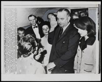 Oath for Johnson on Air Force One: President Lyndon B. Johnson is sworn in as president by Judge Sarah T. Hughes as his wife and Mrs. John F. Kennedy flank him in cabin of the presidential plane -- Air Force One, November 22, 1963
