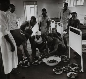 Young men divide food in a hospital ward, Africa