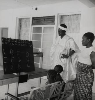Family at home teaching their children the alphabet, likely Dakar, Senegal, Africa