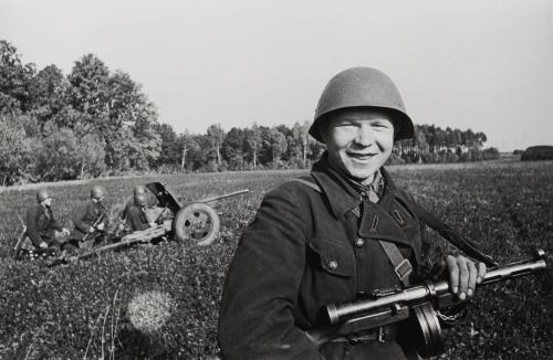 Proud young soldier posing in front of artillery piece