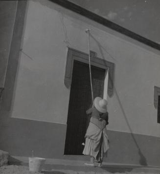 Woman whitewashing her house, Ibiza, Balearic Islands, Spain