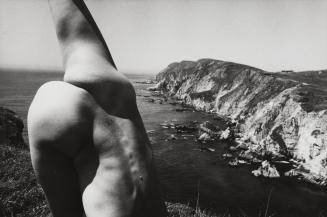 Kate, nude, in a yoga pose on cliff overlooking the ocean