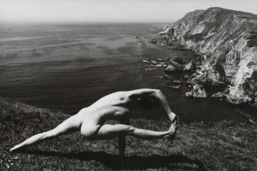 Kate, nude, in a yoga pose overlooking the ocean
