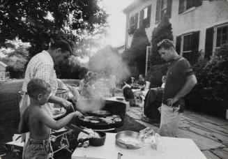 Bobby Kennedy and White House Press Secretary Pierre Salinger grilling hamburgers at family gathering