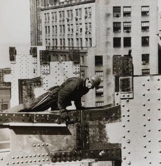 Construction worker climbing over metal beam
