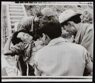 Wounded Cambodian soldier grimaces in pain as he is carried from boat which evacuated him near Mekong River, Cambodia January 11th, 1971, after he was wounded in a firefight with the Viet Cong near Kampong Cham