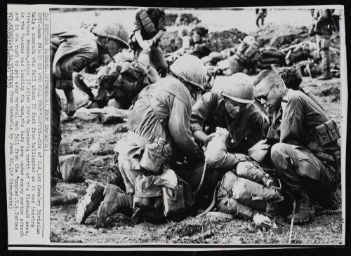 GI’s of the U.S. First Cavalry division help a comrade who fell about 20 feet from helicopter as it was leaving Firebase Bronco about 17 miles inside Cambodia, north of the Fish Hook area on June 25th, 1970. As the helicopter was loading the men, the base came under enemy mortar attack and in the rush to get away several men fell