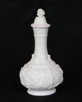 [Parian cologne bottle with stopper glazed interior, stopper has holly-berry pediment and leaves with mottling, bottle has fluted neck trefoil leaf pattern at base of neck, holly berries and leaves in high relief around body with background mottling]