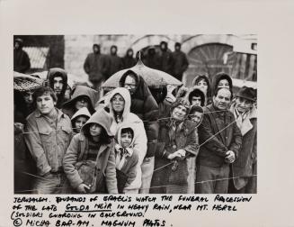 Thousands of Israelis watch the funeral procession of the late Golda Meir in heavy rain, near Mount Herzl. Soldiers guarding in the background, Jerusalem, 1978