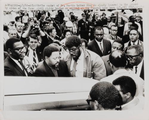 The casket of Dr. Martin Luther King is slowly lowered to the ground by aides of the famed civil rights leader on arrival at the funeral home here, Atlanta, April 5, 1968