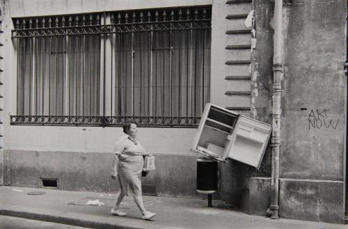 Woman walking past discarded refrigerator, Paris, France