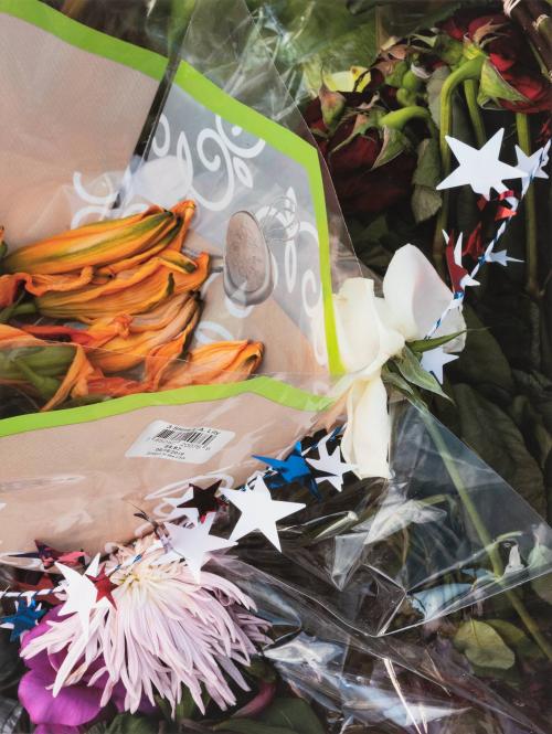 [Flowers wrapped in plastic and string of patriotic stars]