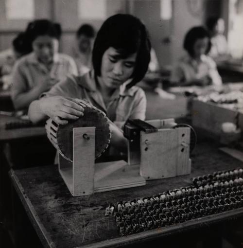 [Female workers at their stations in a factory]