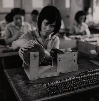 [Female workers at their stations in a factory]