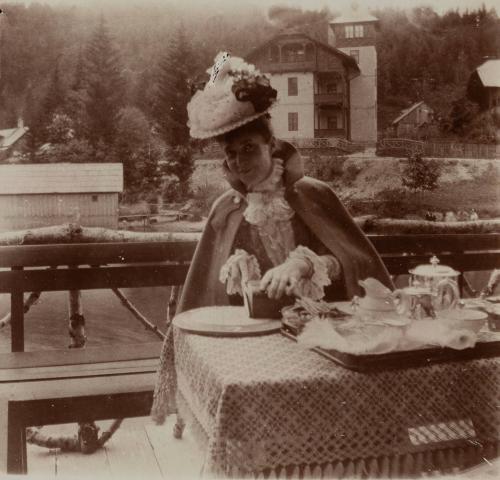 [Woman with floral hat sits at table]
