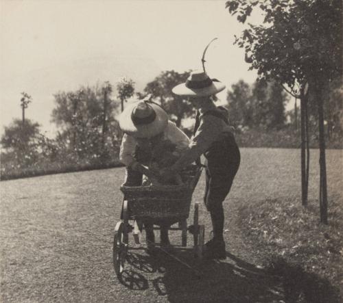 [Two people stand next to small carriage, Villa Billroth, St. Gilgen]