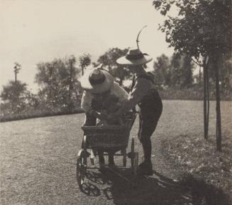 [Two people stand next to small carriage, Villa Billroth, St. Gilgen]