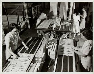 [Female factory worker placing slats on venetian blinds)